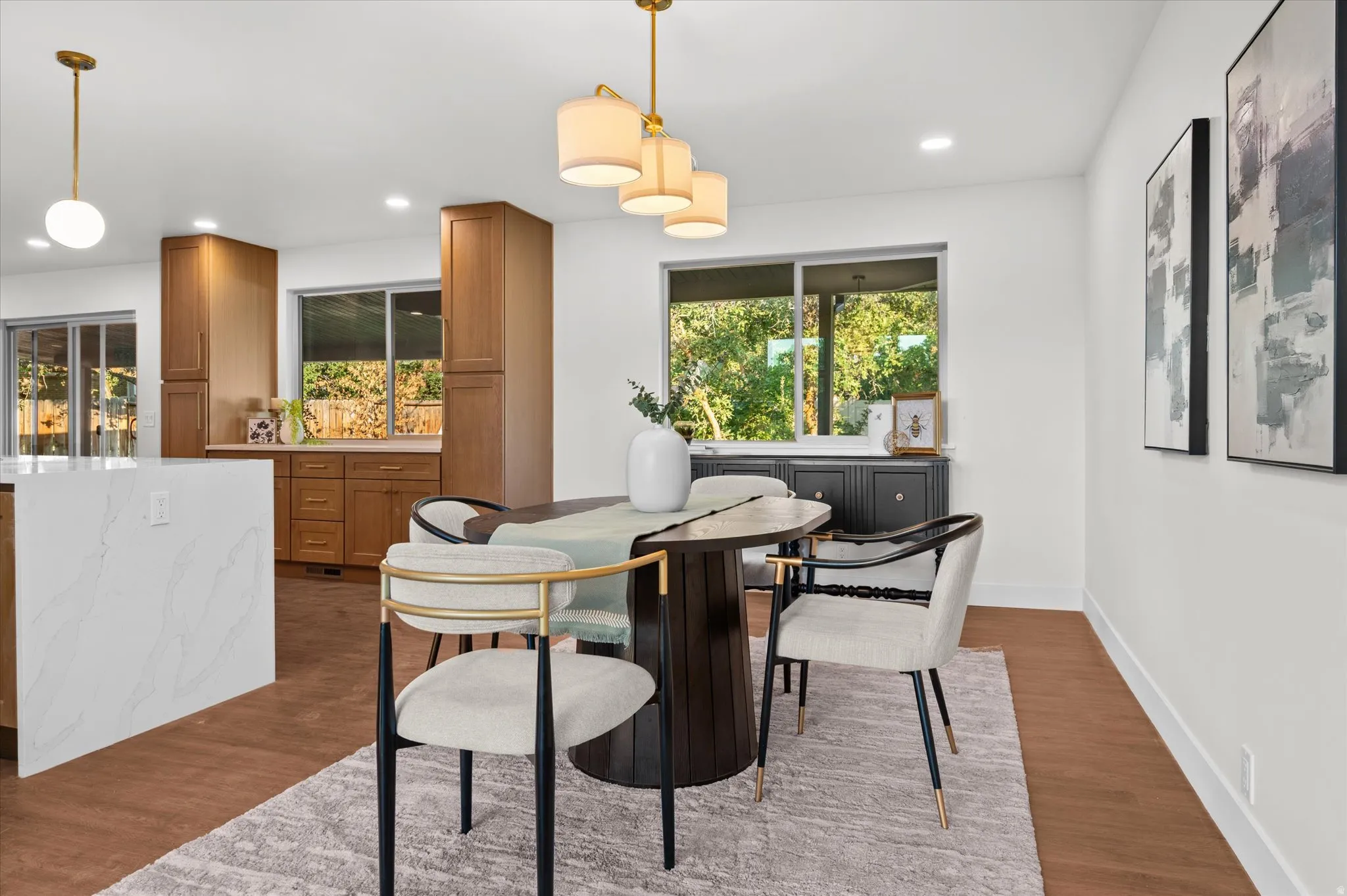 Dining area featuring warm wood-finish flooring and a contemporary chandelier