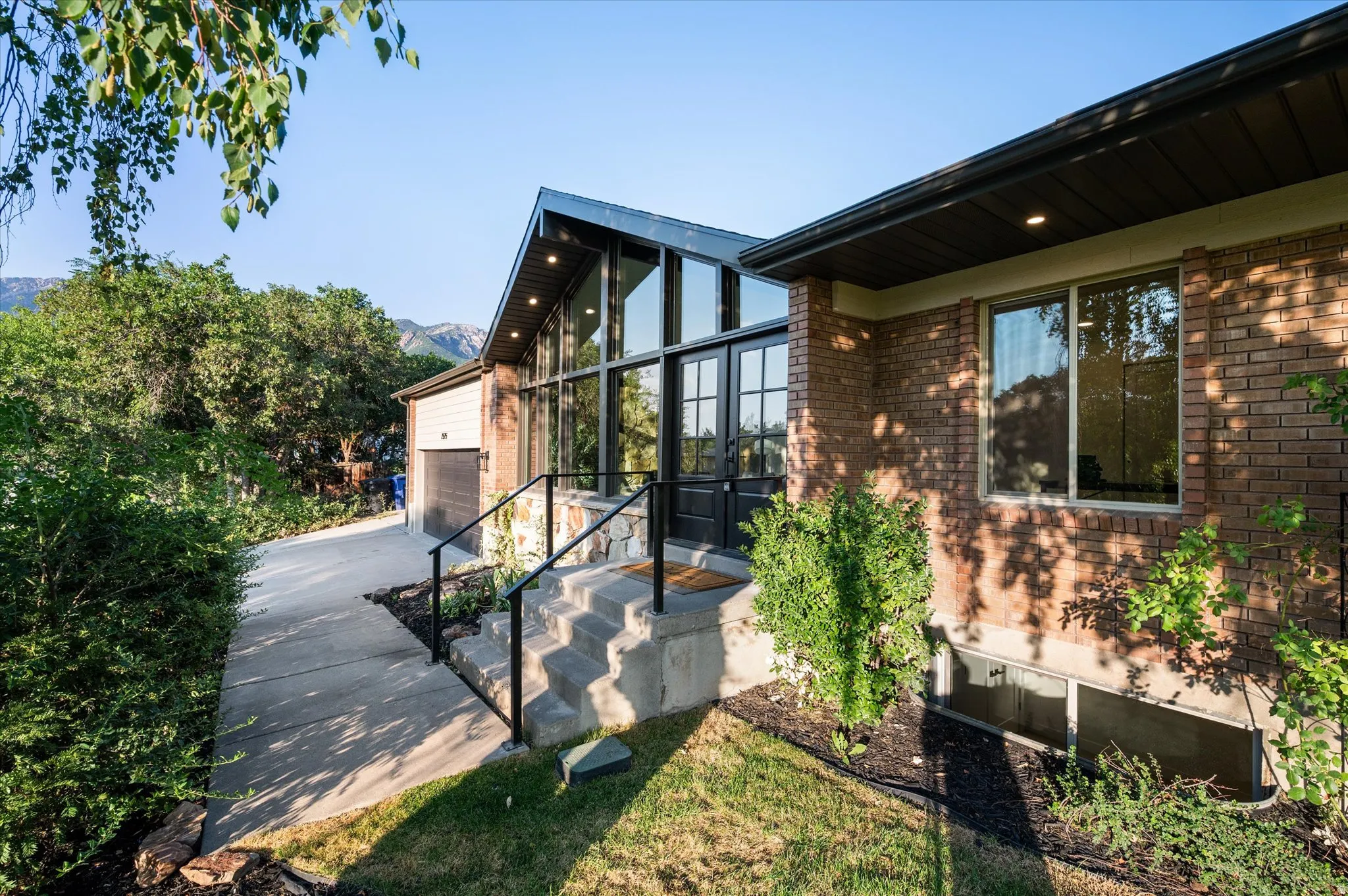 Contemporary residence with a striking glass-paneled entry and black-framed double doors