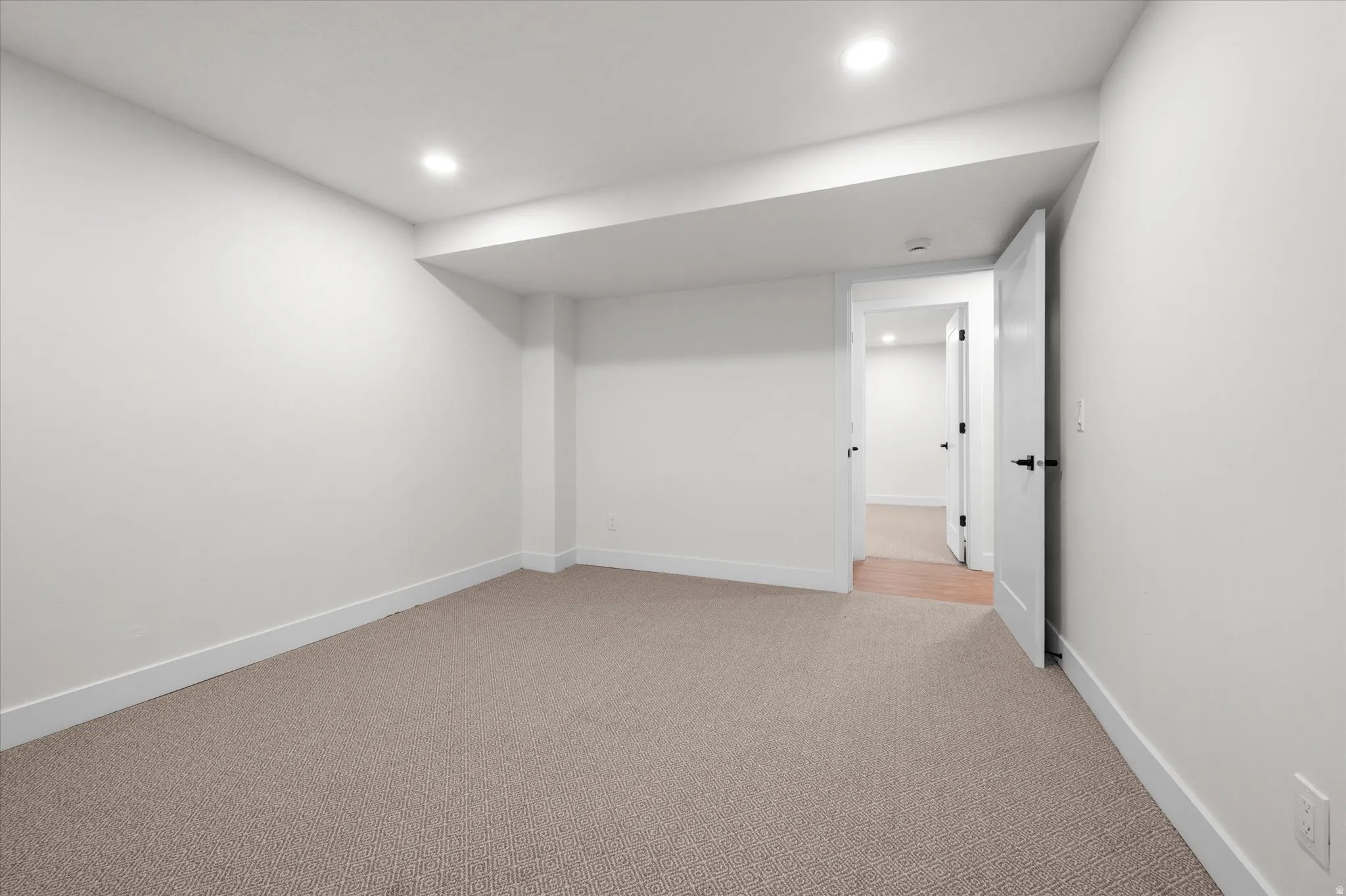 Spacious room featuring neutral carpet flooring, white walls, recessed lighting, and white trim