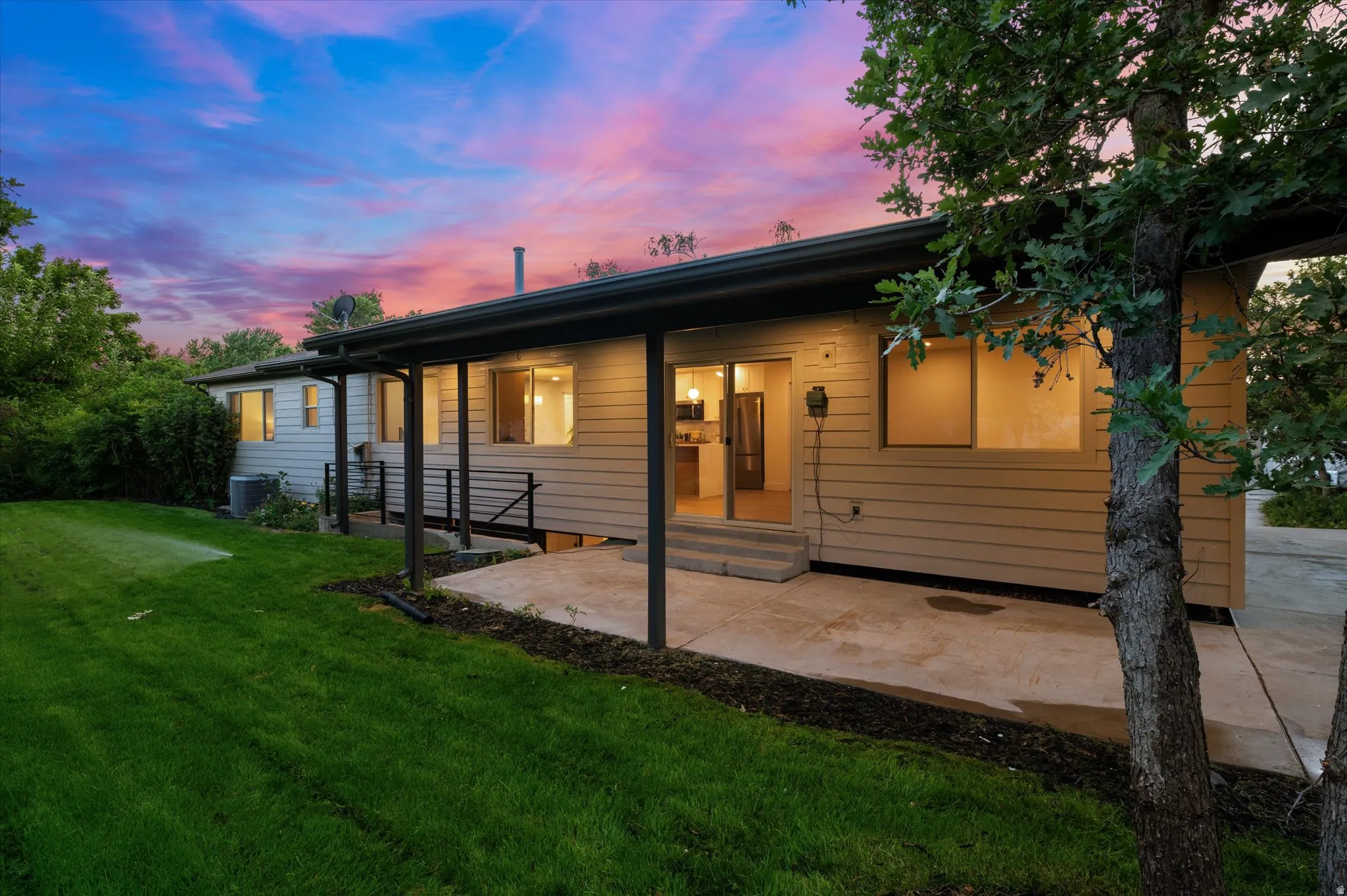Exterior featuring a covered patio, tan horizontal siding, and a manicured lawn