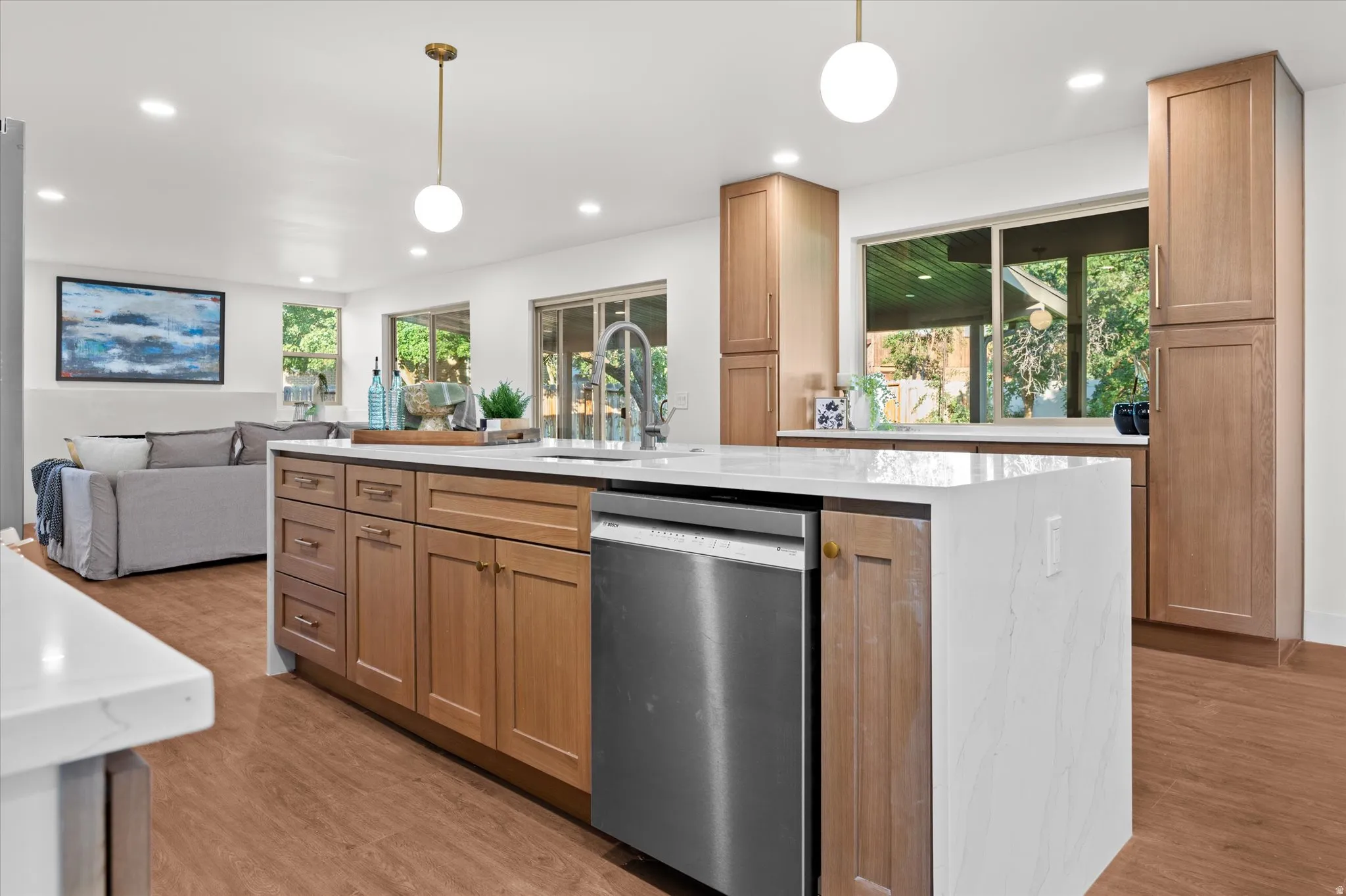 Spacious kitchen featuring a large island with white countertops, wood-finish flooring, recessed lighting, and ample cabinet storage