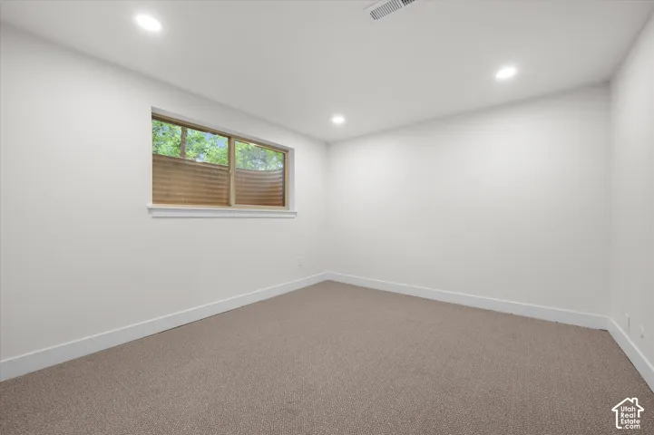 Carpeted room with a horizontal window featuring a window well