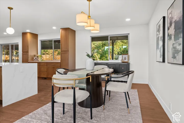 Dining area featuring warm wood-finish flooring and a contemporary chandelier