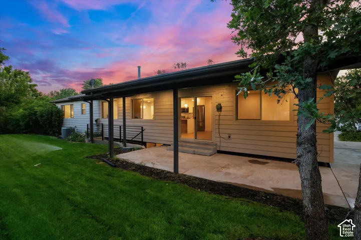 Exterior featuring a covered patio, tan horizontal siding, and a manicured lawn