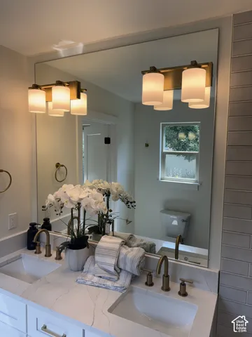 Dual vanity with integrated rectangular sinks, white cabinetry, and brass-finish hardware