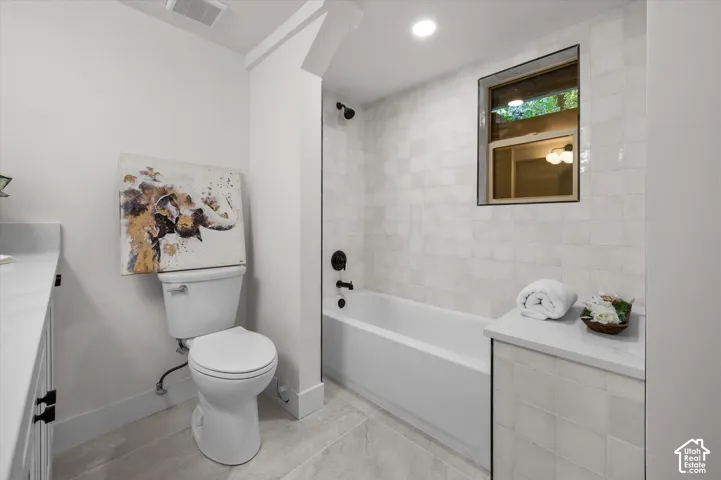 Bathroom featuring a windowed shower-tub combination, matte black fixtures, and light-toned tile surrounds