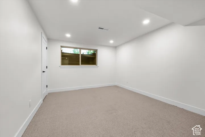 Neutral tone wall finishes with recessed lighting and light-colored carpeting