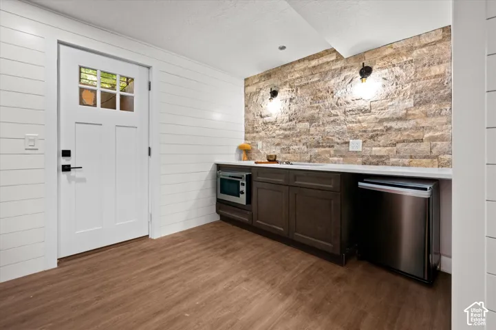Wet bar featuring an integrated sink, built-in microwave, and undercounter refrigerator