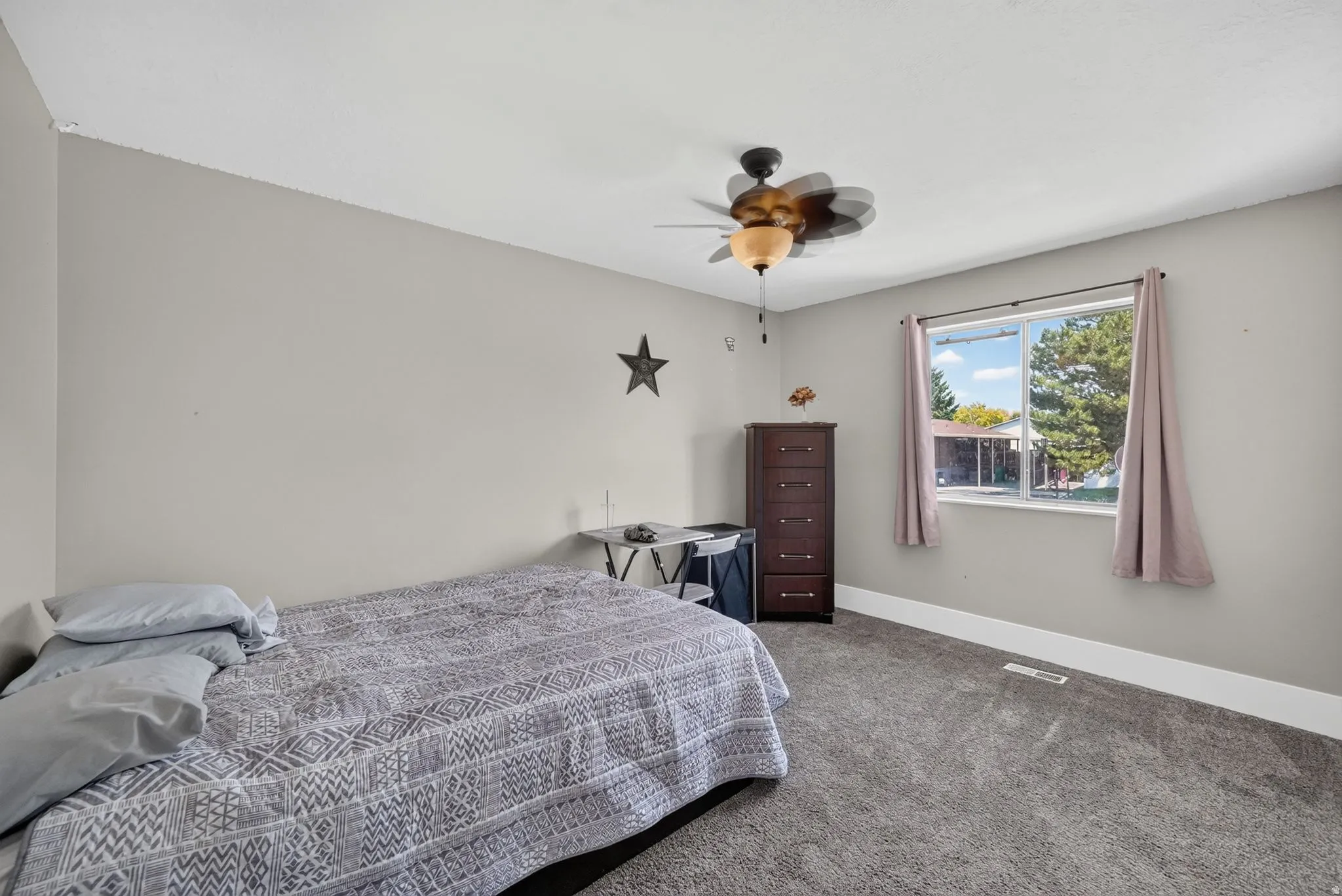 Carpeted flooring, light gray wall paint, white window trim, and a ceiling fan with integrated lighting