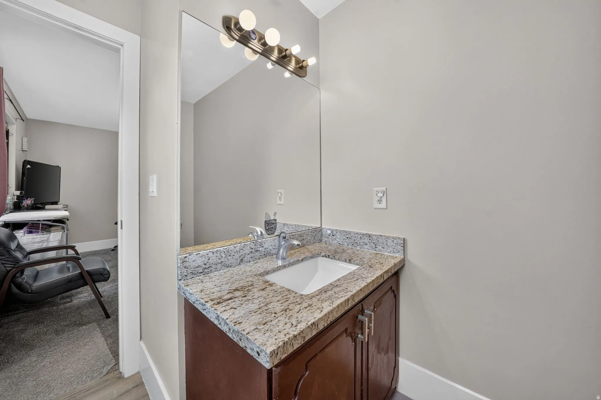 Elegant bathroom vanity featuring rich wood cabinetry, speckled stone countertop, and an undermount sink