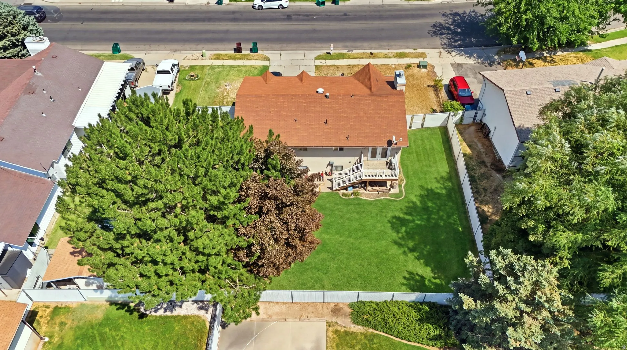 Expansive residential lot featuring a brick-exterior home with a pitched roof, set on manicured grounds with mature shade trees and established landscaping