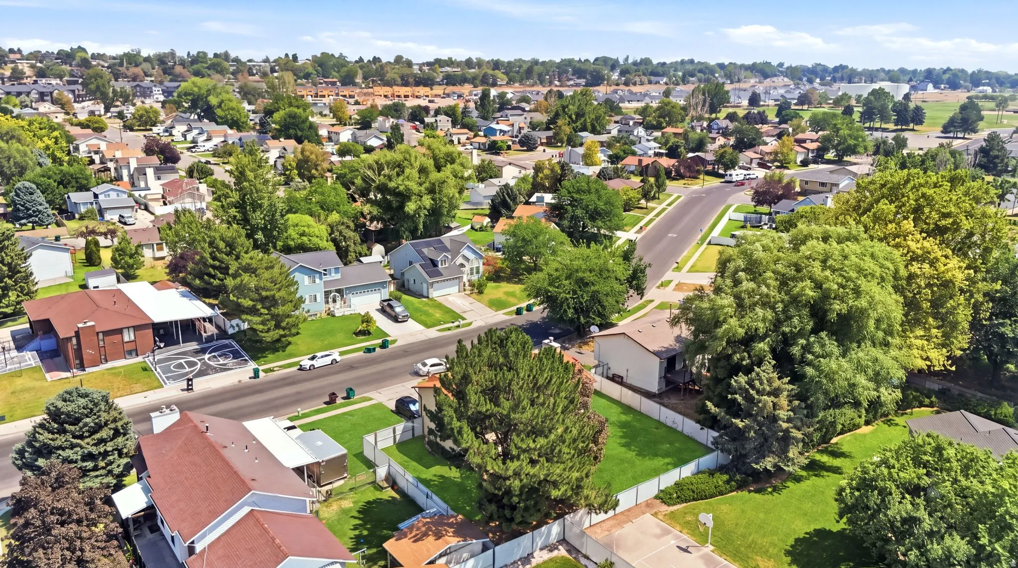 Residential neighborhood featuring mature trees, paved streets, and a mix of single-family homes