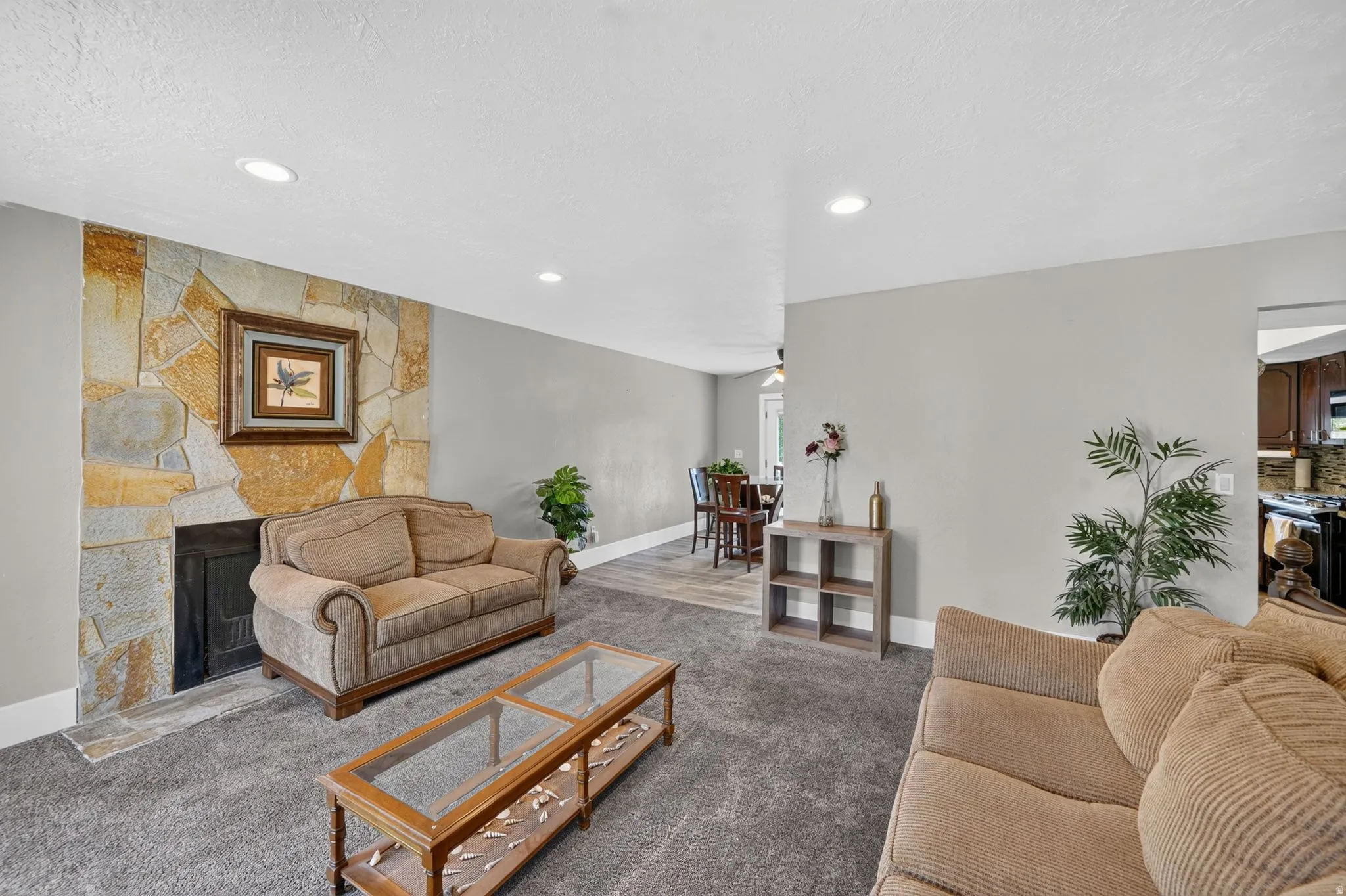 Spacious living room featuring a fireplace with decorative tile surround, recessed ceiling lighting, neutral wall finishes, and plush seating areas