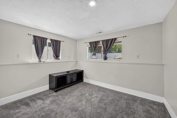 Recessed lighting, two windows, textured ceiling, light gray walls, and gray carpet