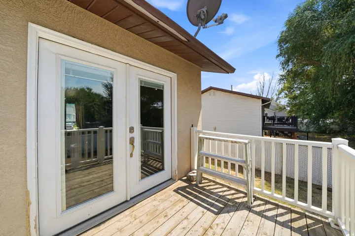 Spacious composite deck featuring pressure-treated wood decking, white aluminum railings with vertical balusters, and direct access via French doors from the home's interior
