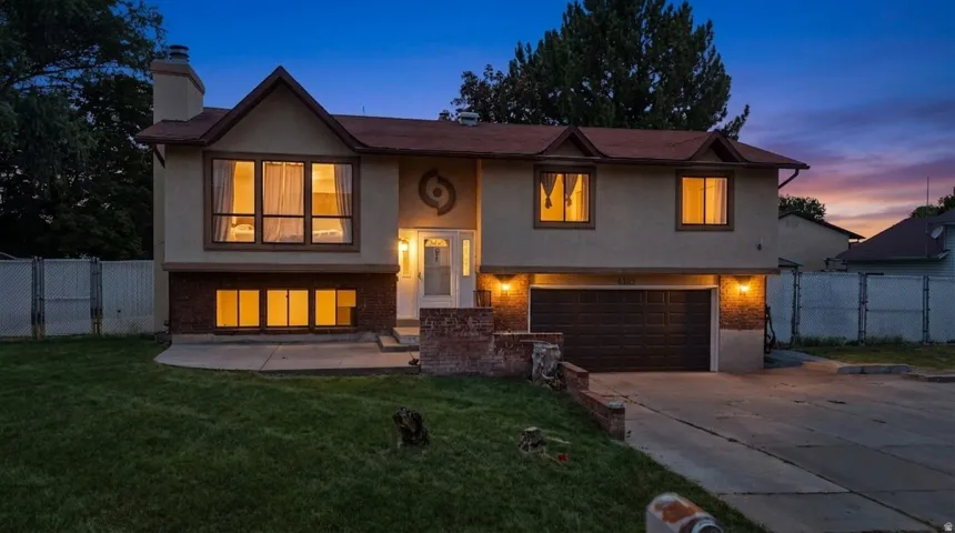 Exterior featuring stucco siding, brick accents, a two-car garage, and multiple windows