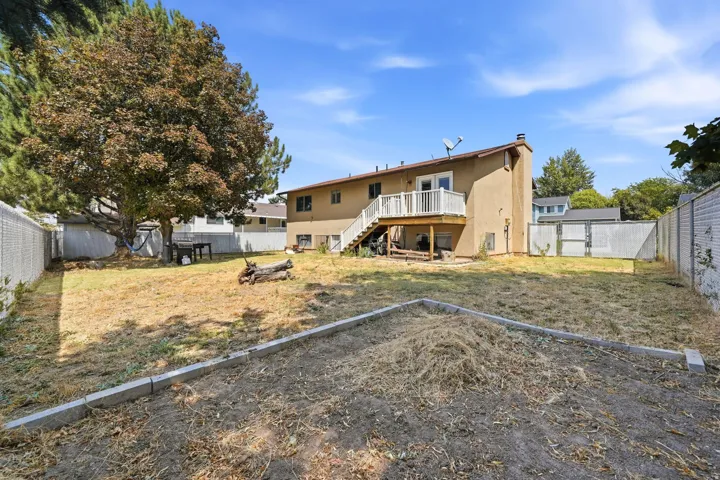 Spacious backyard with mature shade trees, level grounds, and metal fencing