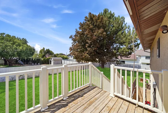 Elevated composite deck with white vinyl railing overlooking manicured lawn and mature landscaping