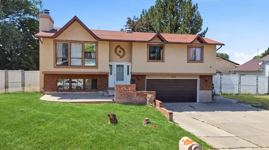 Two-story stucco exterior with a prominent chimney, attached garage, and a sloped front lawn