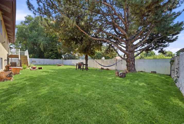 Expansive lawn with mature trees and a white chain-link fence