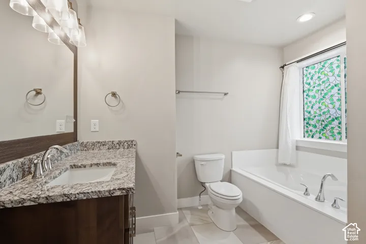 Bathroom featuring a wood-finish vanity with a granite countertop and an undermount sink