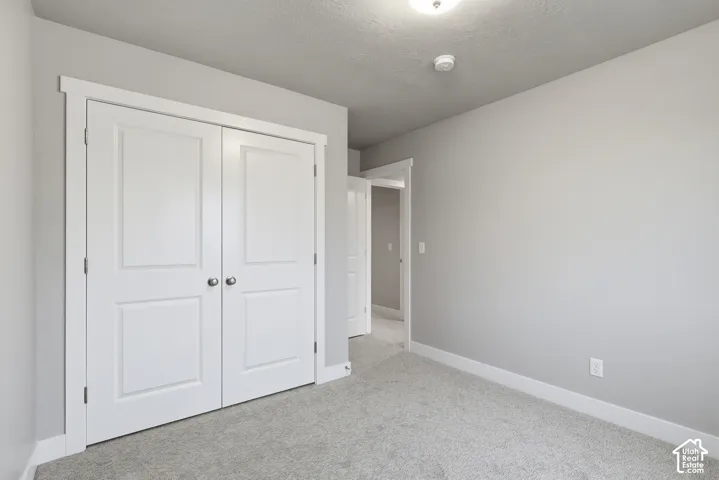 Bedroom featuring plush grey carpeting, light grey wall paint, and white trim