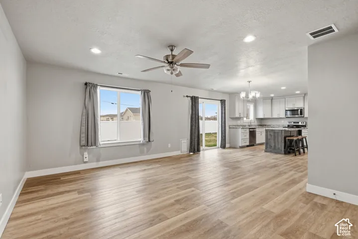 Open-concept living area featuring wood-finish flooring, a ceiling fan, recessed lighting, and light grey wall tones