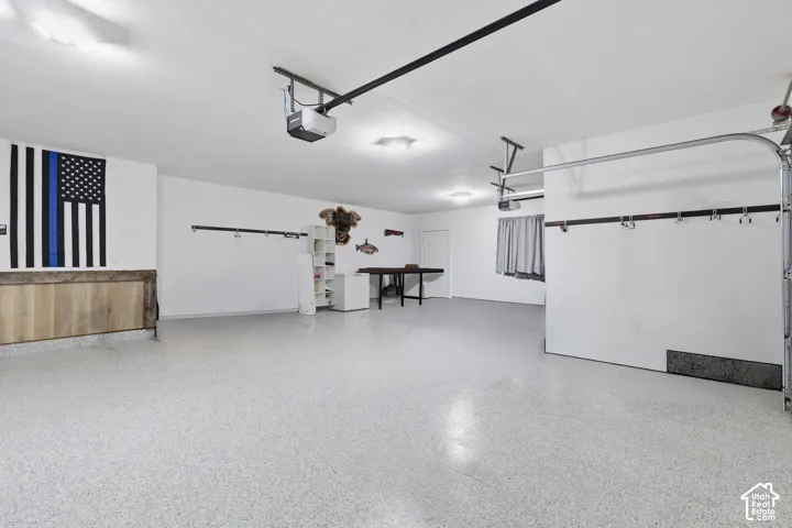 Spacious garage featuring a light-colored epoxy floor, white walls, and built-in overhead lighting
