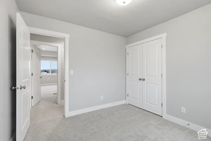 Neutral-toned room featuring a double-door closet, soft carpeting, and white trim