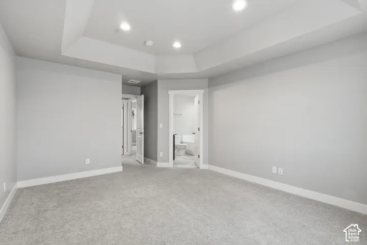 Recessed ceiling with integrated lighting, neutral wall tones, and plush carpeting