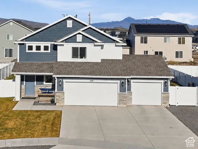 Two-story residence with a stone and siding exterior, featuring an attached two-car garage and a landscaped front yard