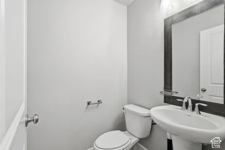 Pedestal sink with chrome faucet, framed mirror, and wall-mounted vanity lighting