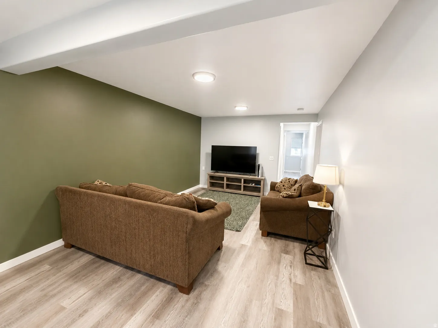 Open concept living area featuring wood-finish flooring, recessed lighting, and a neutral color palette with an accent wall