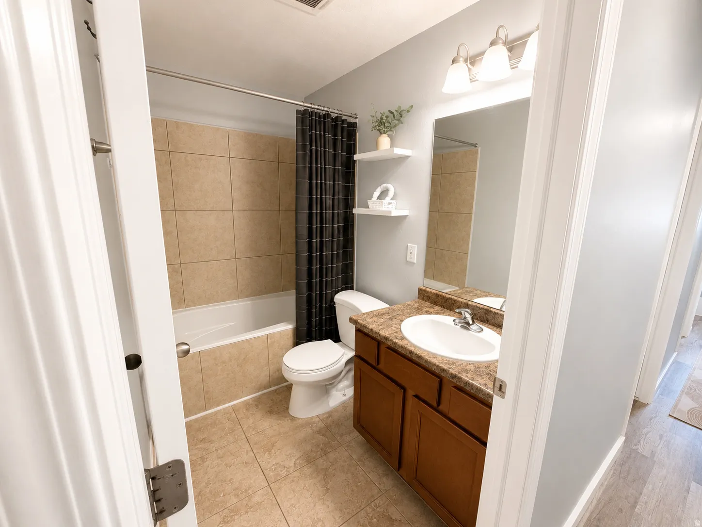 Bathroom featuring a tub/shower combination with tan wall tiling, a vanity with a laminate countertop, and tile flooring