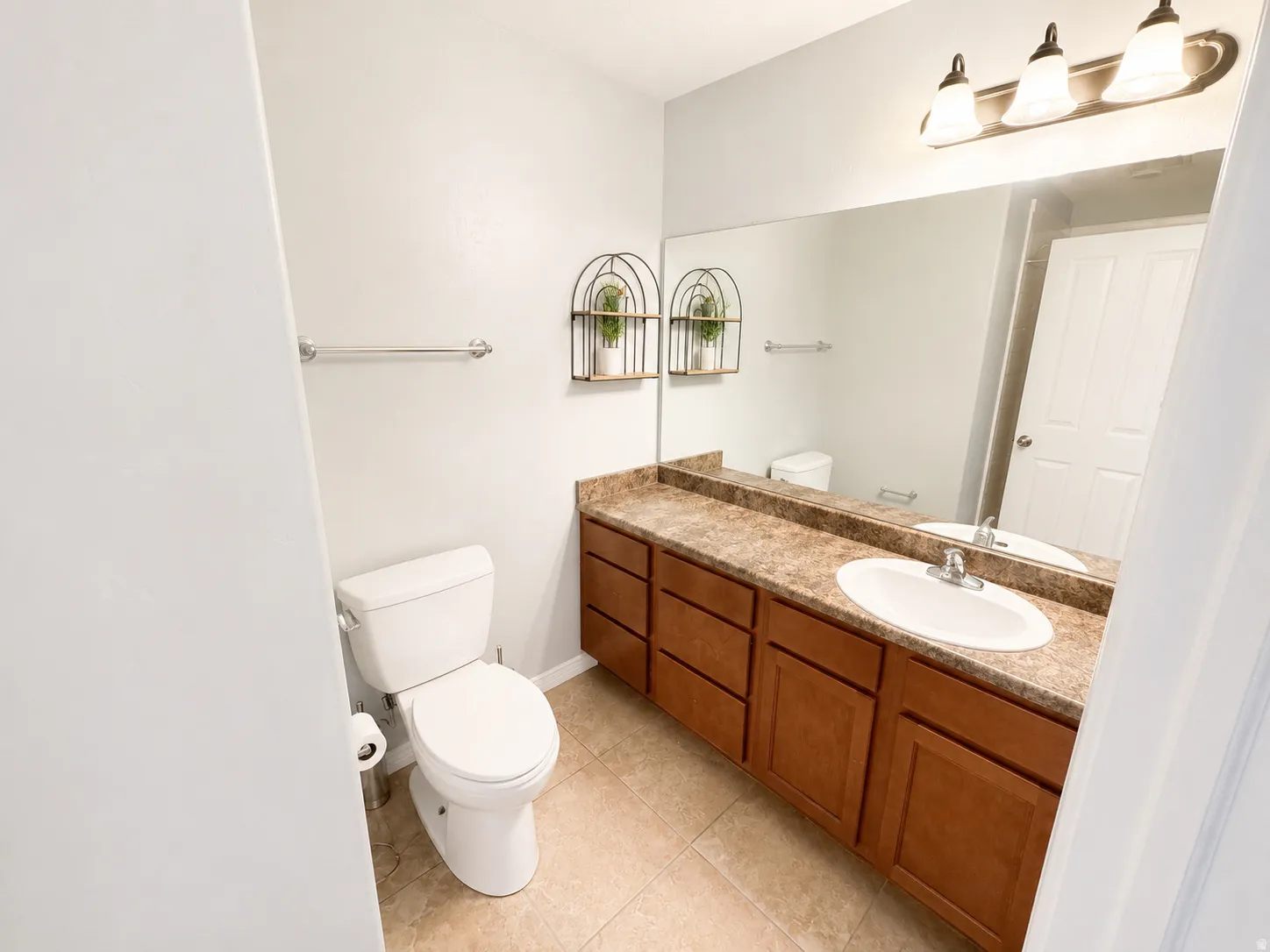 Bathroom featuring a single vanity with a laminate countertop, integrated sink, and wood-finish cabinetry