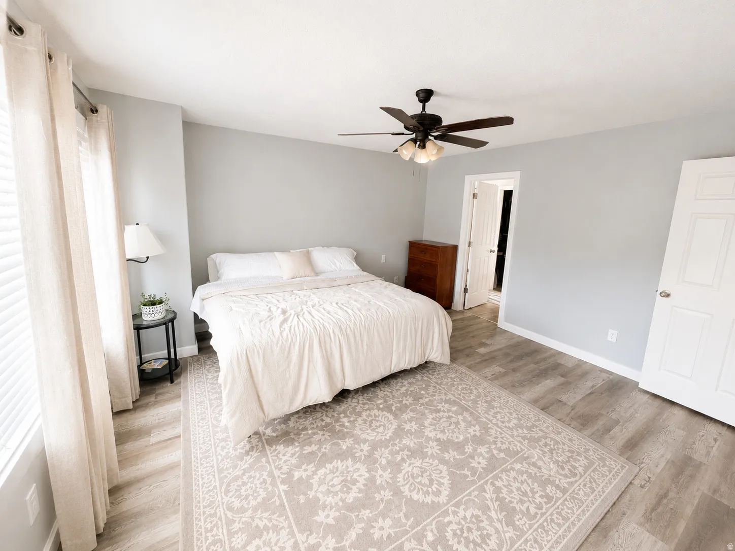 Spacious primary bedroom featuring neutral wall finishes, wood-finish flooring, and a coordinating area rug