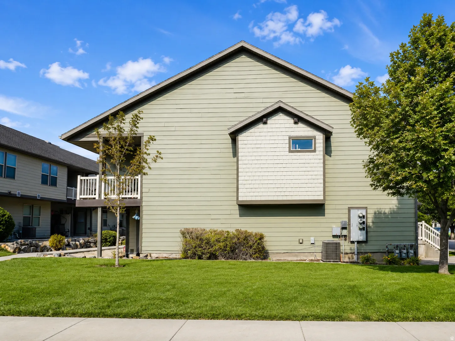 Spacious two-story residence featuring light-colored vinyl siding, a peaked roofline with gabled entry, and a single upper-level window