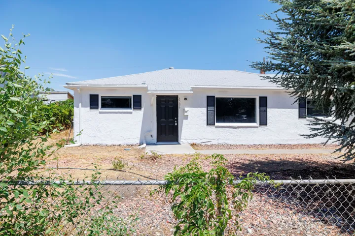 White stucco exterior with black shutters and a prominent black entry door
