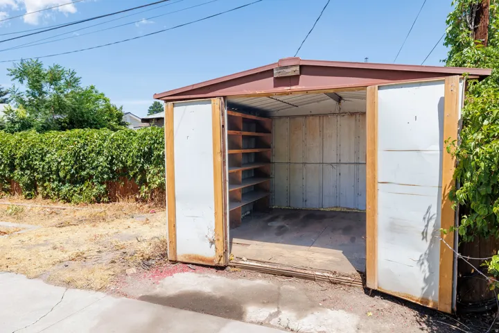 Detached shed featuring a red roof and integrated shelving