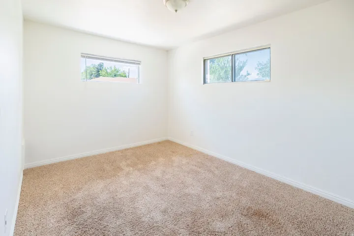 Carpeted room with two horizontal windows, white walls, and a ceiling-mounted light fixture