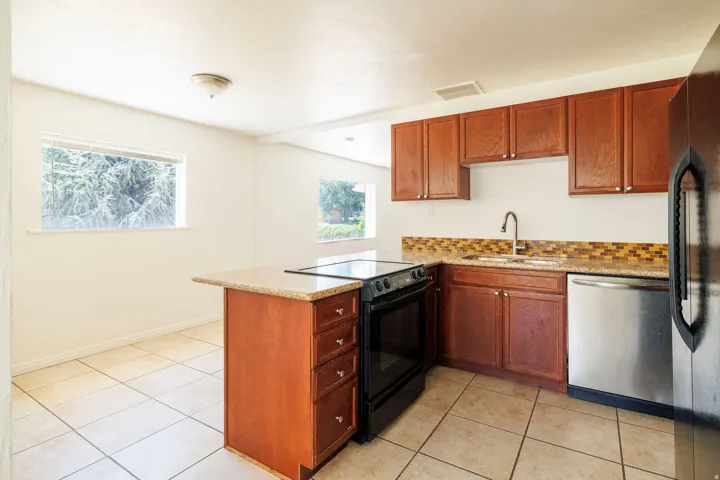 Kitchen featuring wood cabinetry, a mosaic tile backsplash, and light-toned tile flooring