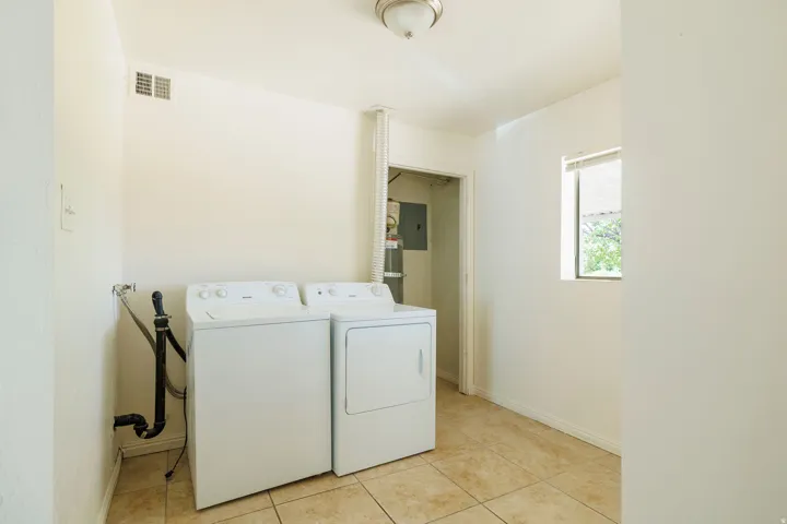 Utility area featuring tiled flooring, a window providing natural light, and a built-in ventilation system