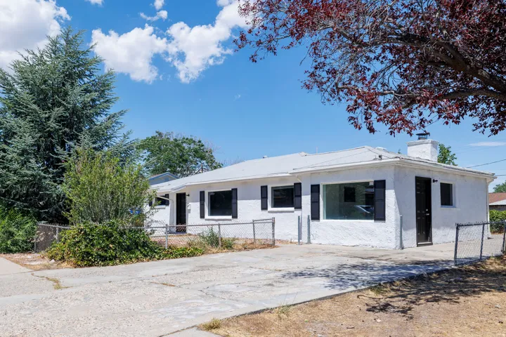 White stucco exterior with black window shutters and a chimney