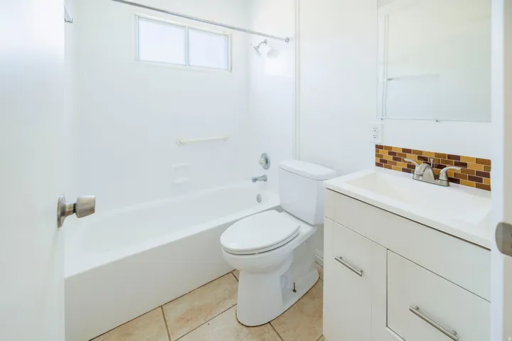 Bathroom featuring a white bathtub, white toilet, and a white vanity with a rectangular sink
