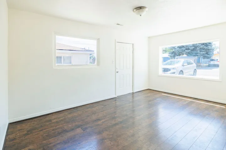 Spacious room featuring wood-finish flooring, white baseboards, and two large windows