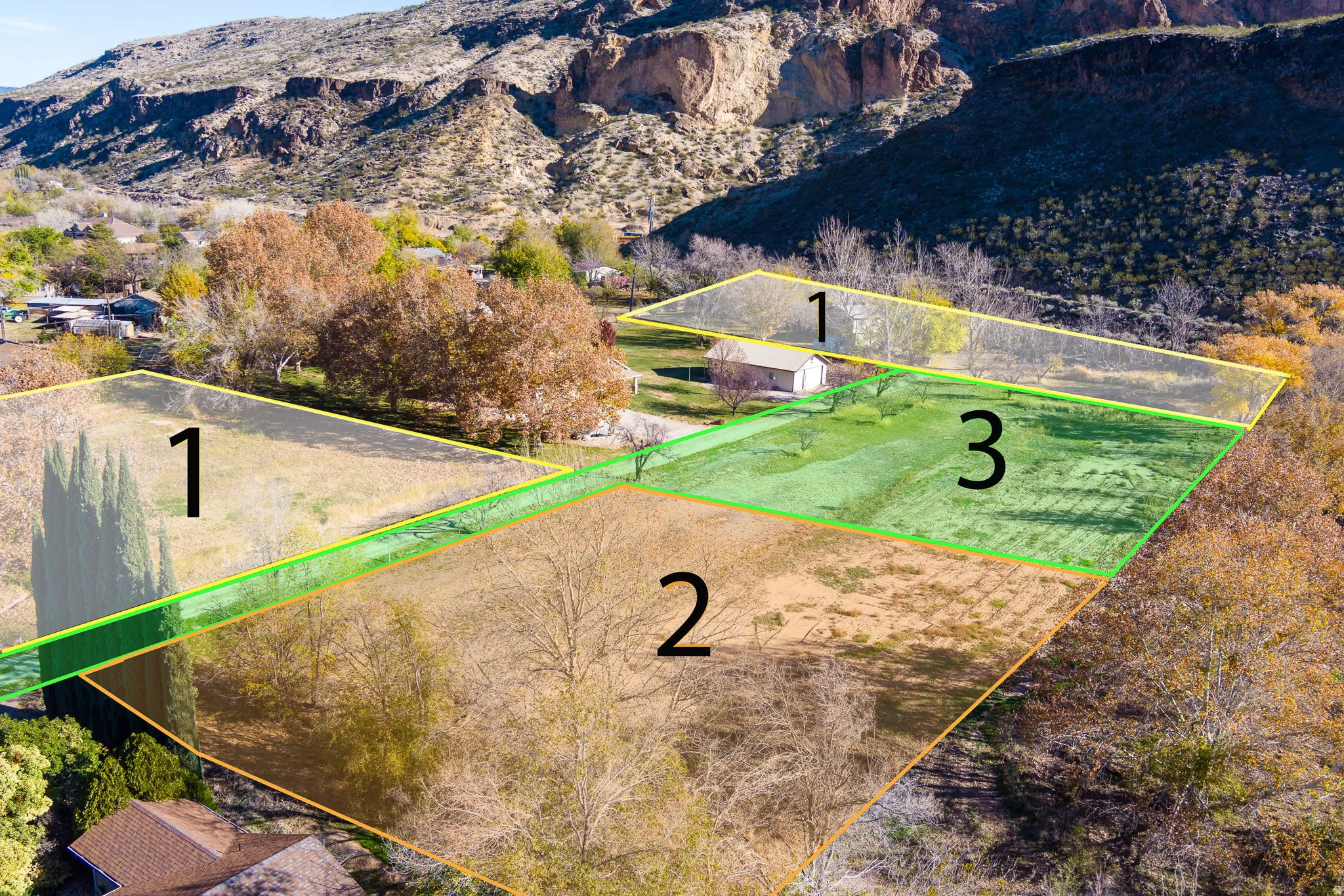 Expansive land parcel with surrounding rugged mountains, featuring varied terrain and mature trees