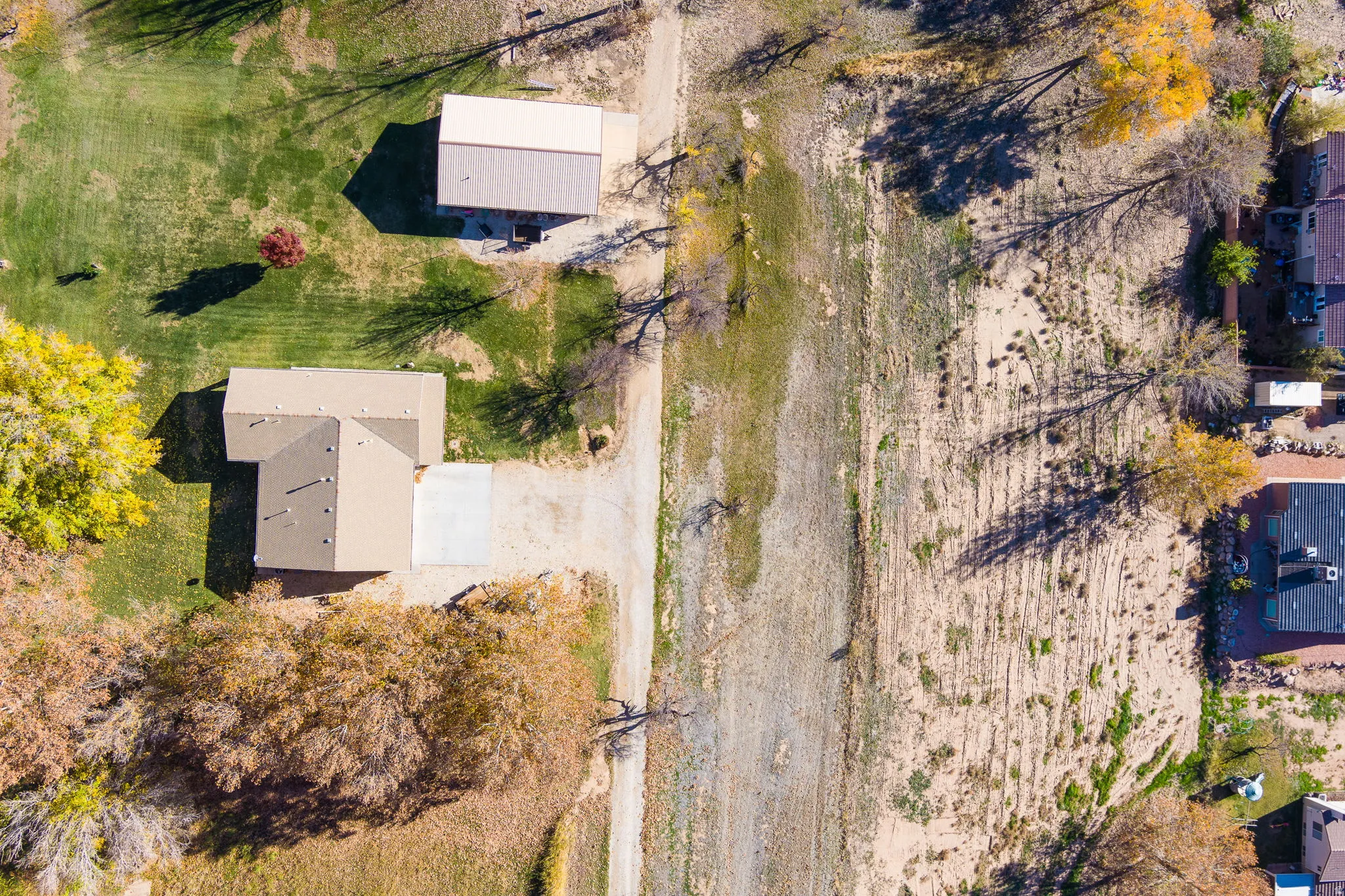 Aerial perspective showcasing a property with a primary residence, a detached auxiliary building, and a driveway