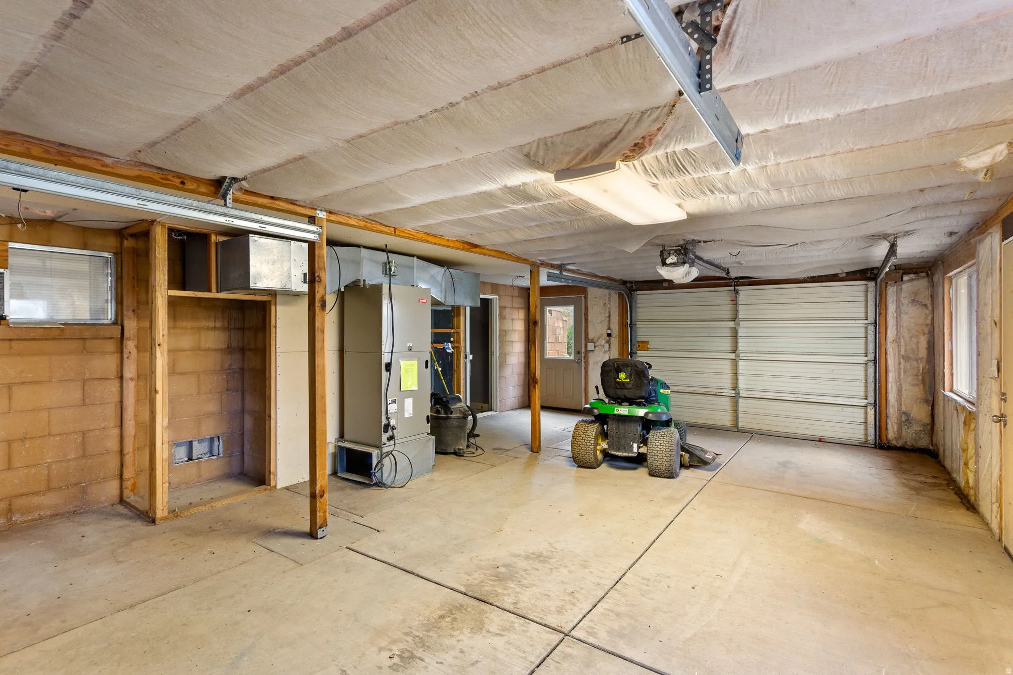 Spacious garage featuring a concrete floor, insulated ceiling, and a large roll-up door