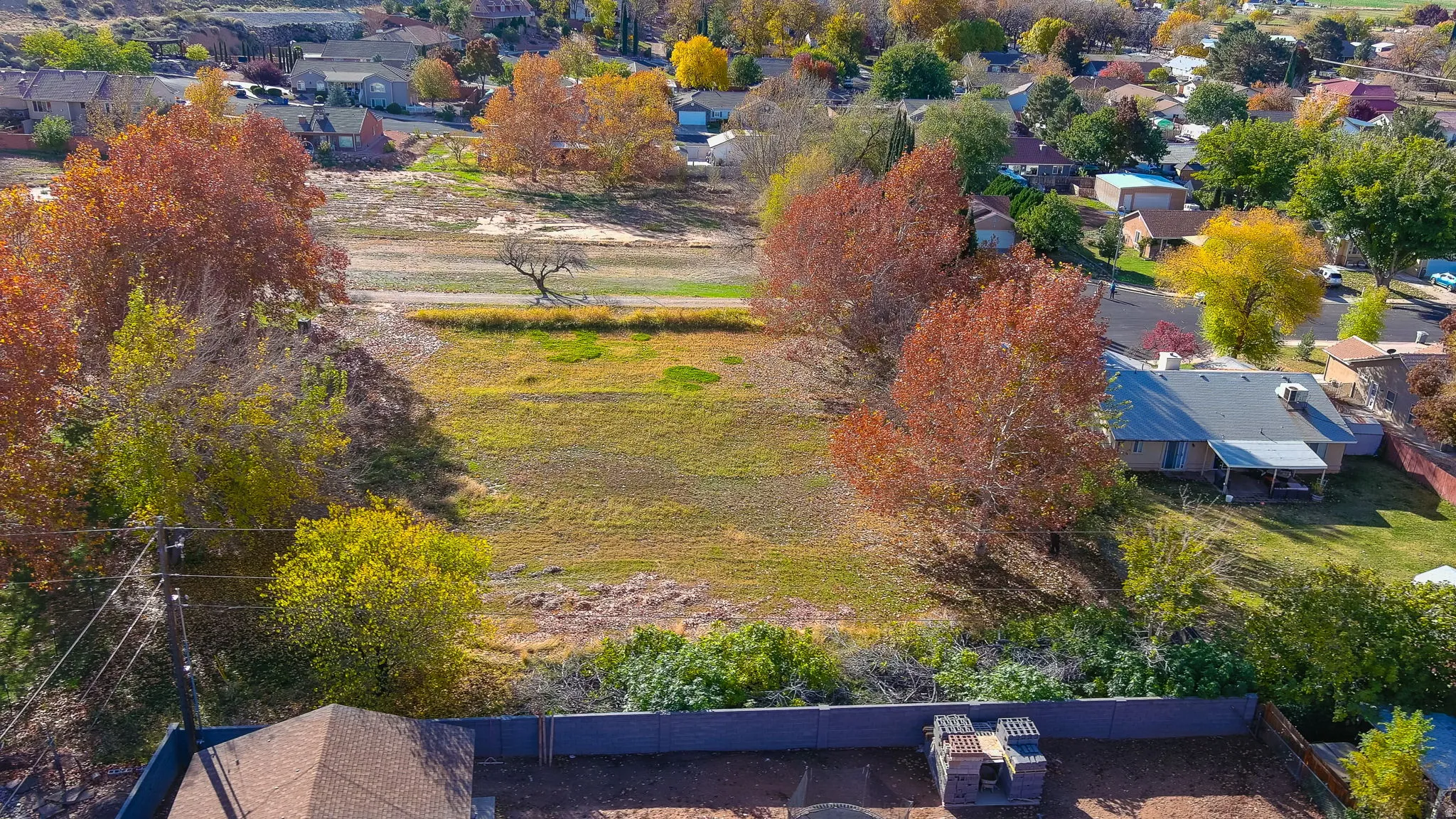 Expansive land parcel featuring open fields and mature trees with vibrant autumn foliage