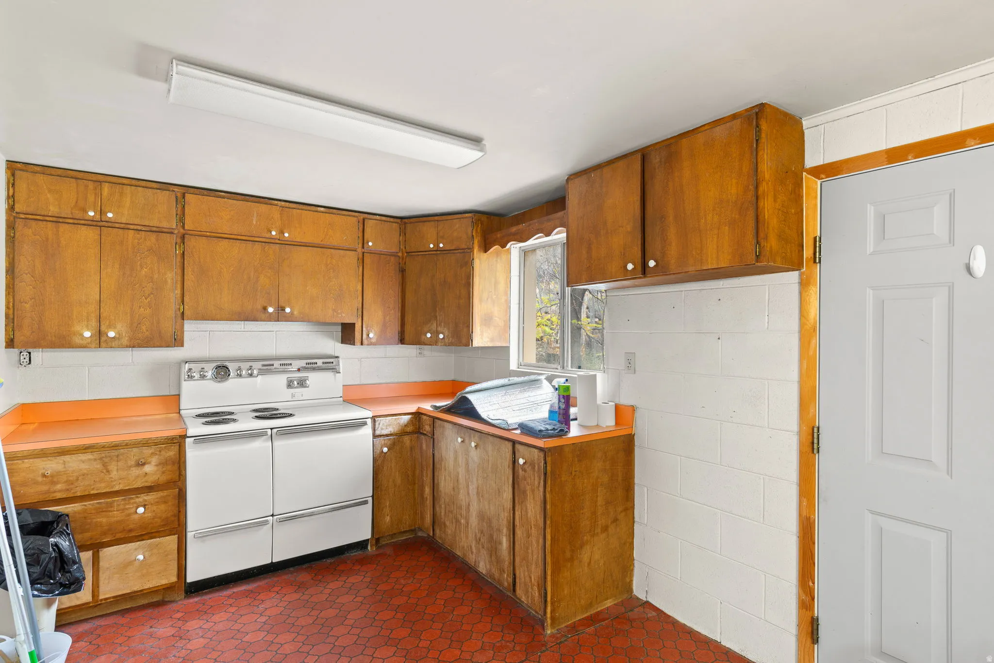 Kitchen with extensive wood-finish cabinetry, solid surface countertops, and white tile backsplash